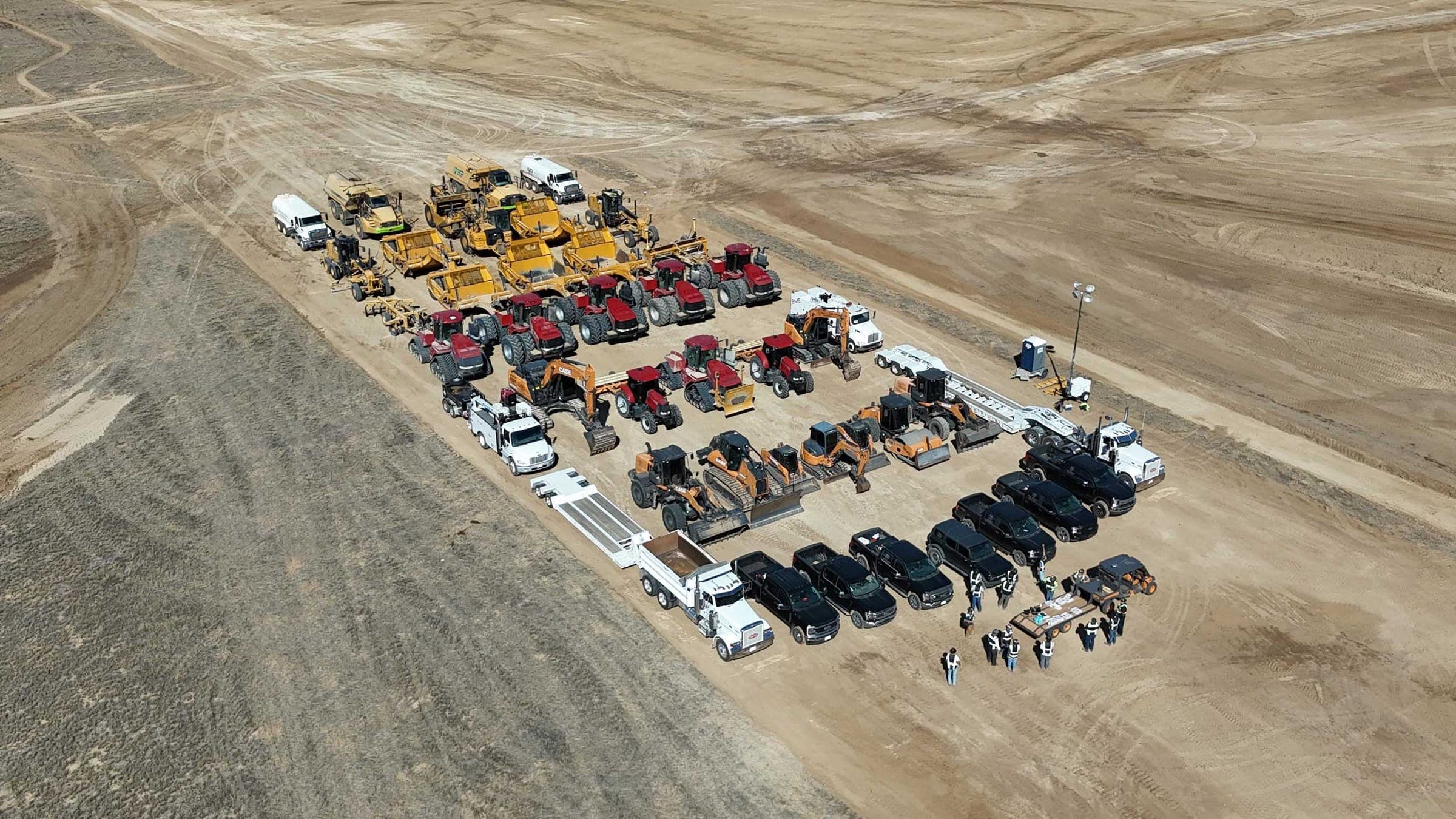Aerial view of BME's equipment yard: rows of scrapers, tractors, dozers, and pickups lined up