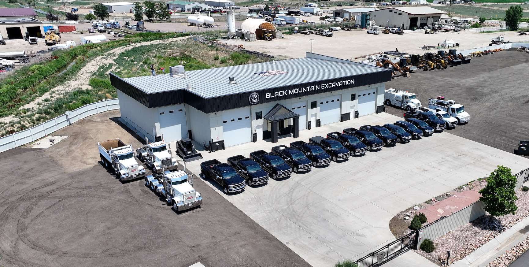Aerial view of the Black Mountain Excavation shop and office, with a row of company pickups parked out front